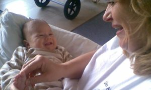 Smilende baby får zoneterapi på skødet af Bettina hos Den Blå Delfin på Amager